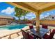 Inviting backyard featuring a pristine pool with a waterfall feature, complemented by an outdoor dining area and lush landscaping at 455 W Honeysuckle Dr, Chandler, AZ 85248