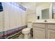 Well-lit bathroom features a toilet, vanity with sink, decorative wallpaper, and a shower with patterned curtains at 6030 W Topeka Dr, Glendale, AZ 85308