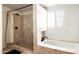Bright bathroom featuring a stand-up shower, white soaking tub, and tan stone tile at 6522 E 2Nd St, Scottsdale, AZ 85251