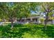 Lush front yard with mature trees shading a charming white brick home with black accents at 6837 E Lafayette Blvd, Scottsdale, AZ 85251