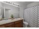 Bright bathroom featuring double sinks with a decorative cactus and a shower/tub with a patterned curtain at 7343 W Hughes Dr, Phoenix, AZ 85043