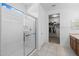 Bright bathroom featuring a glass-enclosed shower, leading into a walk-in closet space at 7343 W Hughes Dr, Phoenix, AZ 85043