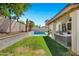A serene backyard featuring a sparkling pool, well-manicured lawn and a covered patio seating area at 10102 E Dreyfus Ave, Scottsdale, AZ 85260