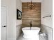 Bright bathroom with a freestanding bathtub and an eye-catching wood accent wall with modern chandelier at 10102 E Dreyfus Ave, Scottsdale, AZ 85260