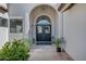Close up of a charming double-door entry accented by an arched doorway, lanterns, and potted plants at 10102 E Dreyfus Ave, Scottsdale, AZ 85260