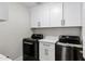 Well-organized laundry room with modern washer and dryer, sleek white cabinets and dark hardware at 10102 E Dreyfus Ave, Scottsdale, AZ 85260