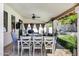 Relaxing covered patio with dining table, TV, ceiling fan, grill and comfortable seating area surrounded by a green lawn at 10102 E Dreyfus Ave, Scottsdale, AZ 85260