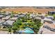 Aerial view featuring community pool and hot tub surrounded by mature trees, with single-Gathering homes in the distance at 14870 W Encanto Blvd # 2138, Goodyear, AZ 85395