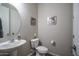 The powder room has a single pedestal sink, a white toilet, and a round mirror hung on the wall at 18731 W San Juan Ave, Litchfield Park, AZ 85340