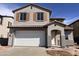 Charming two-story home with a white garage door, beige stucco and tile roof at 22392 W Monona Ln, Surprise, AZ 85387
