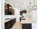 Modern kitchen featuring dark cabinets, granite countertops, stainless steel appliances, and pendant lighting at 24610 W Bowker St, Buckeye, AZ 85326