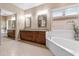 Bright bathroom featuring dual sinks, granite countertops, a soaking tub, and a large mirror at 2612 S Jacob St, Gilbert, AZ 85295