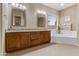 Bright bathroom featuring dual sinks, granite countertops, a soaking tub, and two large mirrors at 2612 S Jacob St, Gilbert, AZ 85295