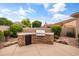 Outdoor kitchen area equipped with a built-in stainless steel grill and a mini fridge set against beautiful landscaping at 2612 S Jacob St, Gilbert, AZ 85295