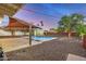 Desert landscaped backyard featuring a covered patio, pool, and shed at 317 E Belmont Ave, Phoenix, AZ 85020