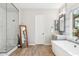 Bright bathroom features a soaking tub, walk-in shower with marble surround, and wood look ceramic tile at 3648 E Fargo St, Mesa, AZ 85205