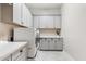 Laundry room includes white cabinets, counters, and modern washer and dryer with white herringbone tile flooring at 3648 E Fargo St, Mesa, AZ 85205