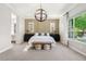 Bright main bedroom with modern chandelier, decorative accents, plantation shutters, and a large window for natural light at 3648 E Fargo St, Mesa, AZ 85205
