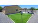 A view of the synthetic lawn, gazebo, and patio space in the backyard, bordered with gravel and a block fence at 38086 W Isabella Ln, Maricopa, AZ 85138