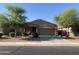 Charming single-story home featuring a two-car garage, desert landscaping, and mature trees at 38086 W Isabella Ln, Maricopa, AZ 85138