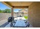 Covered patio with a dining table, a grill, and a view of the landscaped backyard at 38086 W Isabella Ln, Maricopa, AZ 85138