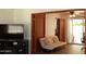 An open living room and adjacent sunroom with a futon couch, TV, and light hardwood floors at 3942 N 38Th St, Phoenix, AZ 85018