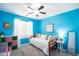 Bright blue bedroom with a comfortable daybed, colorful storage, and a ceiling fan at 4110 E Brighton Way, San Tan Valley, AZ 85140