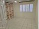 Bedroom with a large window with plantation shutters, a built in bookcase and white tiled flooring at 4116 E Lupine Ave, Phoenix, AZ 85028