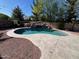 Pool with rock waterfall feature, desert landscaping, string lights, hot tub, and privacy wall at 4130 E Megan St, Gilbert, AZ 85295