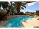 A beautiful pool surrounded by desert landscaping and mature palm trees on a sunny day at 4441 E Sunnyside Ln, Phoenix, AZ 85032