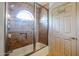 An updated tiled shower includes a built-in niche, glass door, arched window, and modern shower head at 4441 E Sunnyside Ln, Phoenix, AZ 85032