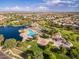 Aerial view of a community with a large lake, pools, a playground, and green spaces at 44454 W Oster Dr, Maricopa, AZ 85138