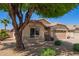 Cozy one-story home with desert landscaping, featuring a mature shade tree and a two-car garage at 44454 W Oster Dr, Maricopa, AZ 85138