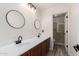 Bright bathroom featuring dual sinks, dark hardware, wood-look floors, and a glass walk-in shower at 5322 N Oro Vista Ct, Litchfield Park, AZ 85340
