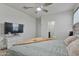A bright bedroom includes a ceiling fan, tv, and ensuite bath at 7812 W Payson Rd, Phoenix, AZ 85043