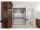 Bathroom featuring a glass shower with a white and blue tile design and a tall, dark wooden cabinet at 8637 E Via De La Escuela --, Scottsdale, AZ 85258