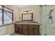 Bathroom with double sinks, granite counters, wood cabinets, and a tiled shower with glass doors at 1001 W Northern Ave, Phoenix, AZ 85021