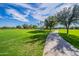 Expansive green space with a winding path, framed by mature trees and blue skies at 1187 E Frances Ln, Gilbert, AZ 85295