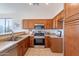 Well-lit kitchen with stainless steel appliances, warm wood cabinets, and tile floors at 1187 E Frances Ln, Gilbert, AZ 85295