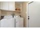 Laundry room with white washer and dryer, storage cabinets, and shelving for organization at 13411 N 50Th St, Scottsdale, AZ 85254