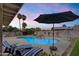 Inviting backyard pool with lounge chairs, shade umbrella, decorative string lights and desert landscaping at 13411 N 50Th St, Scottsdale, AZ 85254