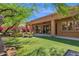View of a landscaped backyard with synthetic grass, covered patio, grill, and green trees at 13914 E Laurel Ln, Scottsdale, AZ 85259