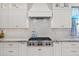 Gourmet kitchen featuring white cabinetry, Wolf range, and stylish range hood at 13914 E Laurel Ln, Scottsdale, AZ 85259