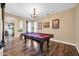 A game room with a pool table with a burgundy felt, wood flooring, and chandelier lighting at 15725 W Yucatan Dr, Surprise, AZ 85379