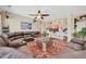 Spacious living room with a large leather sectional sofa, a ceiling fan, and a wall-mounted TV at 15725 W Yucatan Dr, Surprise, AZ 85379