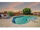 Beautiful backyard pool with desert landscaping, seating, and attractive rock waterfall feature at 15725 W Yucatan Dr, Surprise, AZ 85379