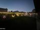 Landscaped backyard with lighting to highlight the lush greenery and fence at 15939 W Post Dr, Surprise, AZ 85374