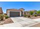 Inviting single-story home with a gray garage door, arched entry, tiled roof, and a low-maintenance landscaped front yard at 19627 W Badgett Ln, Litchfield Park, AZ 85340