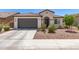 Inviting single-story home with a gray garage door, arched entry, tiled roof, and a low-maintenance landscaped front yard at 19627 W Badgett Ln, Litchfield Park, AZ 85340