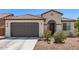 Inviting single-story home with a gray garage door, arched entry, tiled roof, and a low-maintenance landscaped front yard at 19627 W Badgett Ln, Litchfield Park, AZ 85340
